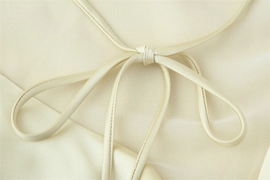 Detailed close-up of ivory woven fabric neck strap with a handmade ribbon knot detail