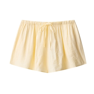 Detail of cream-colored crinkle fabric shorts with elastic waist and decorative bow tie