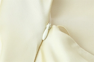 Close-up of invisible drop-shaped zipper on elegant beige satin halter dress fabric