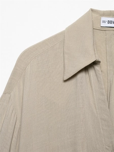 Detail of khaki linen shirt featuring refined collar stitching and pleated shoulder texture