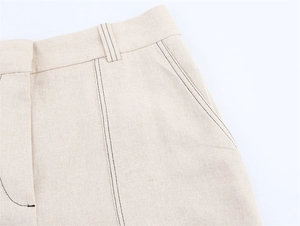 Détail des surpiqûres contrastées sur la taille en lin beige et la poche latérale