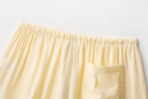 Detail of light yellow crinkled fabric showing the elastic waistband and square pocket