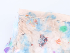 Macro detail of sheer mesh fabric with colorful round sequins and floral embroidery