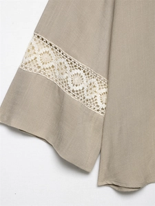 Detail of light brown linen fabric with intricate white crochet lace patchwork trim