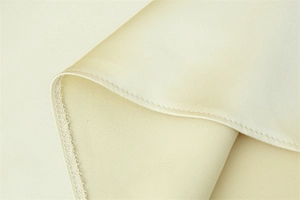 Detailed macro shot of premium satin fabric stitching and ivory silk material texture