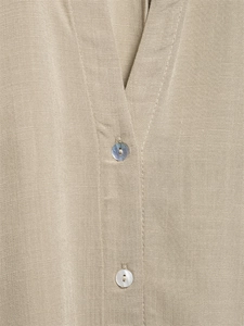 Close-up of beige linen shirt detailing natural fabric texture and shell buttons