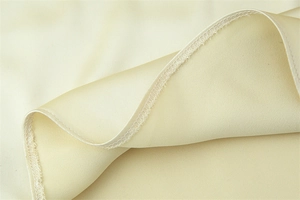 Detail of champagne satin fabric showing fine stitching and smooth material texture