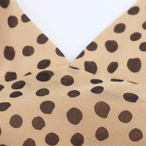 Détail du décolleté en V élégant et de la texture du tissu respirant à pois