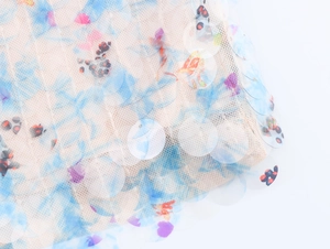 Macro view of mesh fabric featuring colorful floral prints and iridescent sequins texture