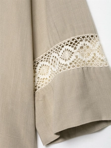 Close-up of beige cotton linen sleeve featuring elegant white hollow lace embroidery detail