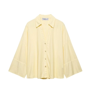 Detail of light yellow linen shirt featuring layered wide cuffs and button-down front