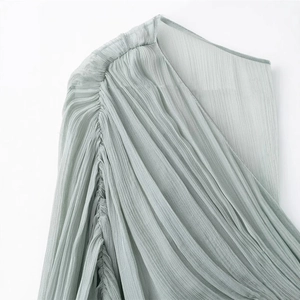 Close-up of light green pleated long dress showing detailed shoulder gathering and texture