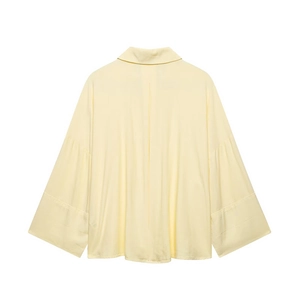 Detail of light yellow linen shirt featuring classic collar and wide draped cuffs