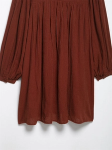 Detail of dark reddish-brown dress with textured fabric and delicate pleated waist design
