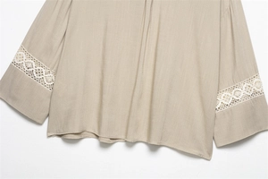 Close-up of linen texture blouse featuring delicate white floral lace sleeves and hem