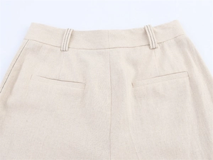 Gros plan des surpiqûres contrastées et poches arrière du pantalon en lin beige clair