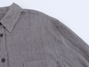 Detailed close-up of striped linen shirt featuring chest pocket and dark buttons