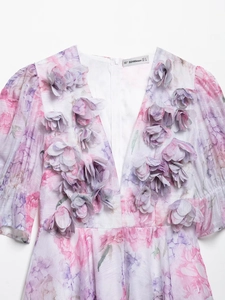 Détail d'une robe fleurie avec des pétales en tissu 3D et des manches bouffantes