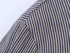 Close-up of shoulder stitching on a blue striped linen blend shirt showing fabric texture