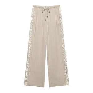 Detail of linen wide-leg pants featuring drawstring waist and crochet lace side panels