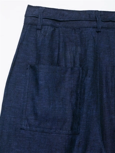 Detail of dark blue linen wide-leg trousers featuring a front pleat and large patch pocket