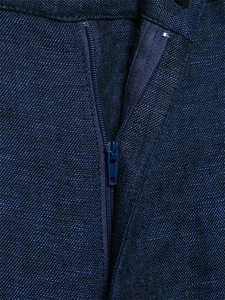 Macro shot of dark blue linen blend trousers showing the zipper fly and fabric texture