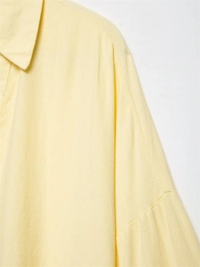 Detail shot of light yellow linen shirt featuring drop shoulder seams and fabric texture