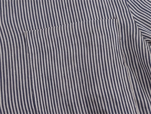 Detail of blue and beige striped linen shirt showing a flat pocket and neat stitching