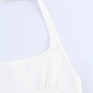 Close-up of white halter neck top featuring elegant pleated details and square neckline