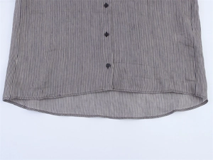 Detail view of navy striped linen shirt featuring black buttons and a curved hemline