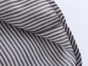 Macro shot of precise overlock stitching on blue and white striped linen fabric shirt