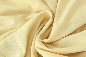 Close-up of soft cream yellow fabric texture with elegant drapes for a midi dress