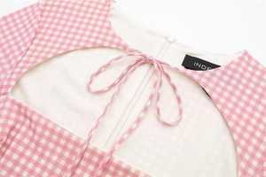 Close-up of pink gingham fabric dress with delicate bow tie detail and brand neck label