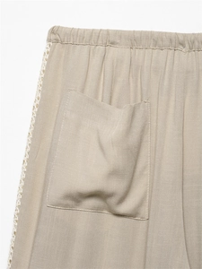 Detail of linen pants showing elastic waist, back pocket and white crochet lace side trim