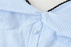 Détail de l'encolure en V avec rayures bleues, dentelle noire et bouton plissé central