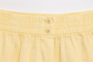 Detailansicht der elastischen Bundfalten und Harzknöpfe an der hellgelben Leinenhose