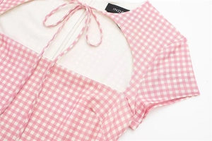 Detailed view of pink gingham mini dress featuring hollow heart neckline and bow tie decoration
