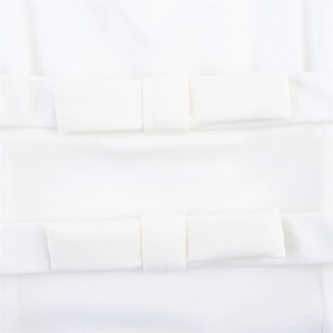 Close-up of white knitted top detailing dual 3D bow accents and halter neckline texture
