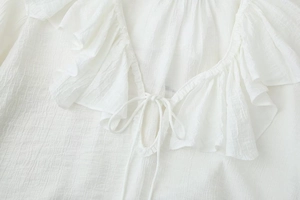 Detailed close-up of French style V-neck white chiffon blouse with ruffle collar and tie-up