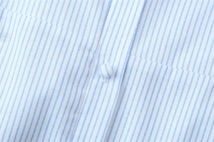 Vue macro d'un tissu en coton à rayures bleues et blanches avec bouton recouvert