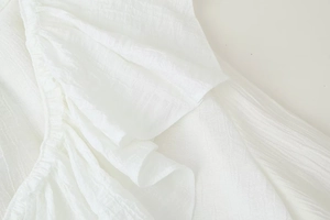 Close-up detail of white chiffon fabric featuring pleated texture and layered ruffles