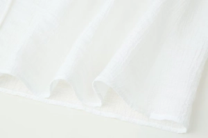 Detail shot of white chiffon blouse with fine vertical crinkle texture and neat hem