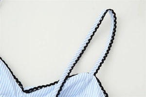 Détail du tissu à rayures bleues et blanches avec bordure en dentelle noire sur la bretelle