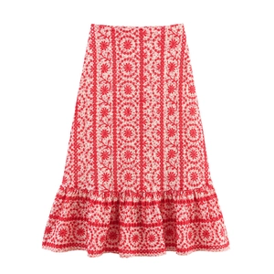 Detail of red floral embroidery on white fabric with ruffled hem for midi skirt