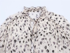 Detail of ruffled stand collar and tie-neck on a beige animal print chiffon blouse