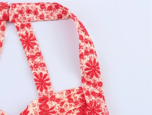 Detailed macro shot of red floral embroidery and button closure on beige fabric