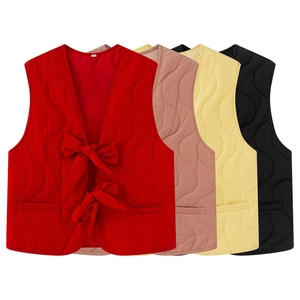 Detail of quilted sleeveless vests with wavy stitching and front bow tie closures