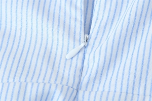 Détail de la fermeture éclair invisible sur une robe à fines rayures bleues et blanches