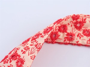 Close-up of red floral embroidery on white cotton fabric with eyelet lace details