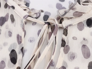 Detail of ruffled tie-neck and pleated chiffon texture with ink spot print